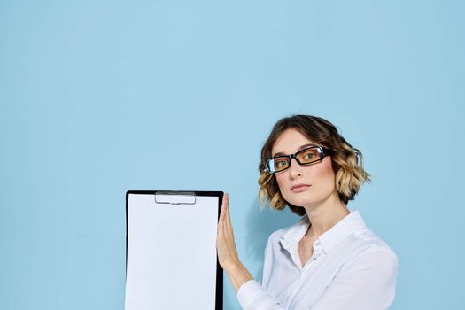 Business woman with documents in a folder on a blue background and in a light shirt glasses on her face. High quality photo