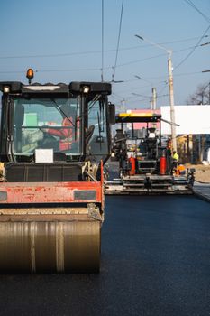 Asphalt road roller with heavy vibration roller compactor press new hot asphalt on the roadway on a road construction site. Heavy Vibration roller at asphalt pavement working. Repairing