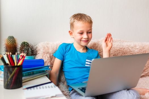 Little young school boy working at home with a laptop and class notes studying in a virtual class. Distance education and learning, e-learning, online learning concept during quarantine