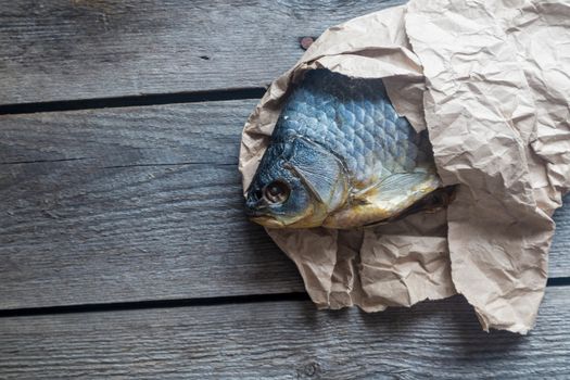 Dried Volga bream vobla in a crumpled kraft paper roll, delicious beer snack, close-up.