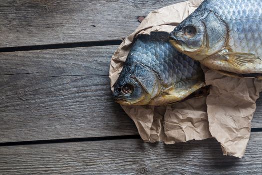 Dried Volga bream vobla in a crumpled kraft paper roll, delicious beer snack, close-up.