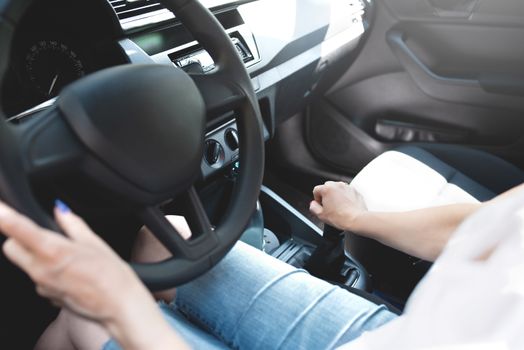Close up woman hands keeping steering wheel while sitting in modern interior of vehicle. Girl driving car at street concept