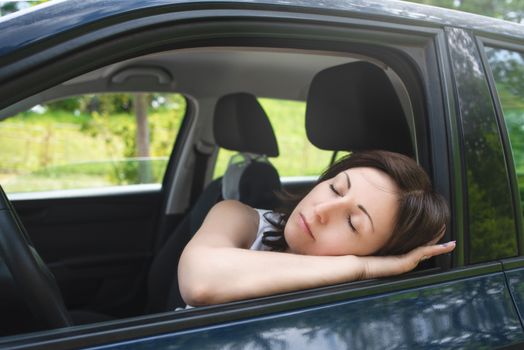 Very tired woman sleeping on a car window.driving safety concept