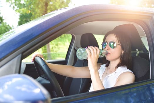 need to drink water every day, anywhere. beautiful brunette behind the wheel. drink driving.