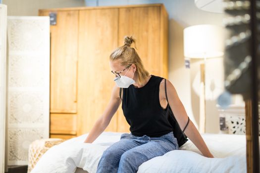New normal during covid epidemic. Caucasian woman shopping at retail furniture and home accessories store wearing protective medical face mask to prevent spreading of corona virus.