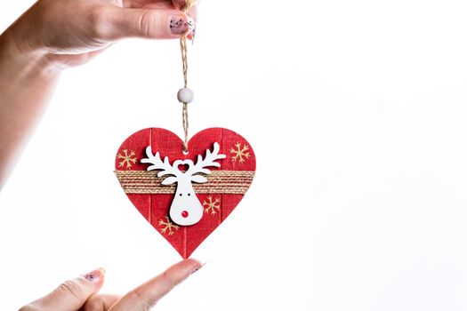 Hand holding heart shaped Christmas decoration isolated on white.