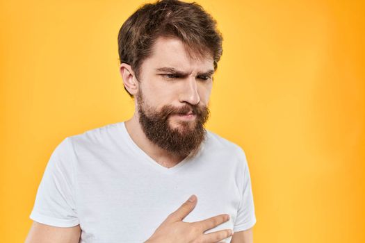 Man with emotional expression white t-shirt close-up studio yellow background. High quality photo
