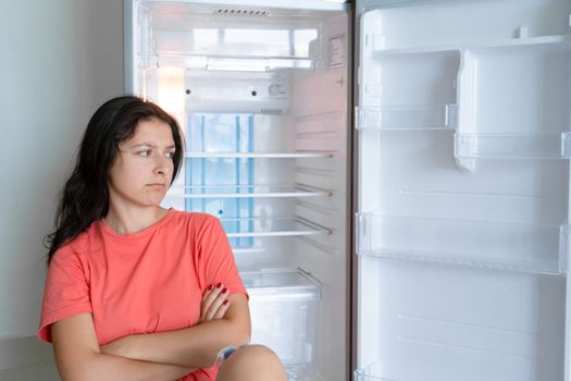The girl is surprised at the empty refrigerator. Lack of food. Food delivery.