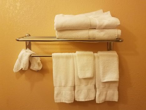 yellow or orange wall with white towels hanging on shelf or rack in bathroom
