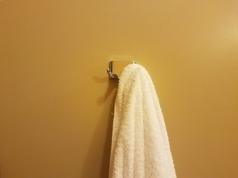 yellow or orange wall with white towel hanging on hook in bathroom