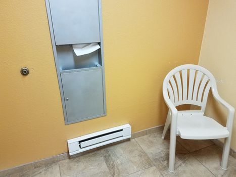 heater with paper towel dispenser and chair in bathroom or restroom