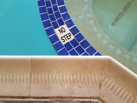 no step sign in swimming pool with blue tiles and water