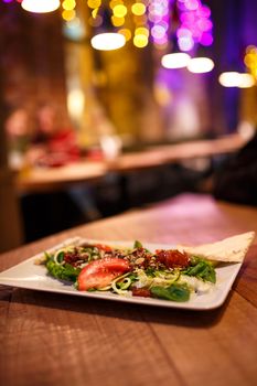 Serve vegetable salad in a white plate. Cozy wooden pub.