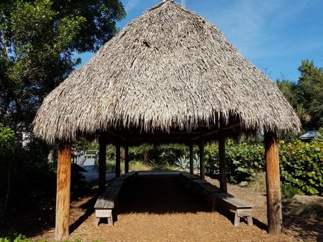 structure or building with grass or thatch roof and wood benches