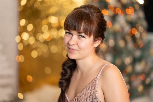 Stylish beautiful girl among sparkles and gerlands at a Christmas party.