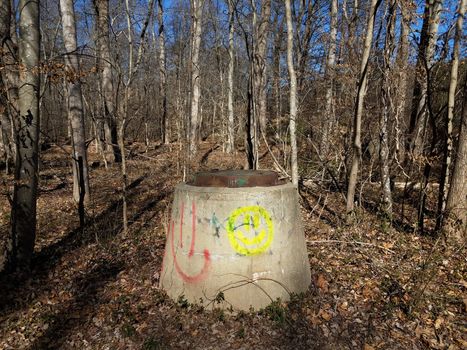 vandalized painted cement sewer entrance in forest or woods