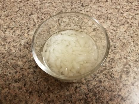 chopped onions and liquid in glass container on counter