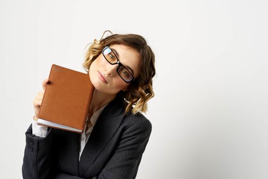 Woman at work with book in hand light background classic suit glasses head. High quality photo