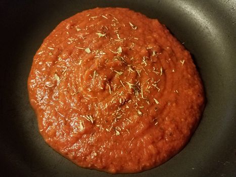 red tomato sauce in frying pan or skillet with herbs