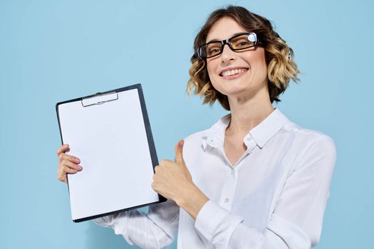 Business woman with documents in a folder on a blue background and in a light shirt glasses on her face. High quality photo