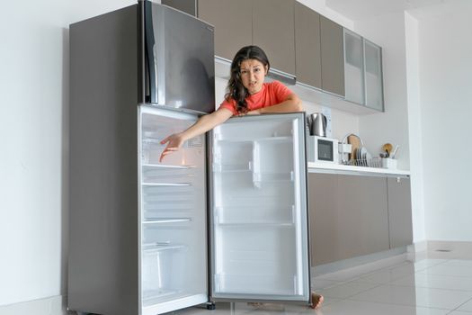 The girl is surprised at the empty refrigerator. Lack of food. Food delivery.