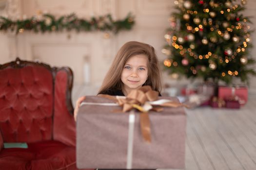 A little girl opens a Christmas present from Santa. Christmas tale. Happy childhood.