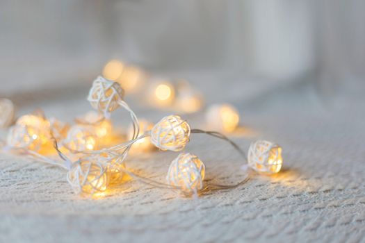 .Christmas rattan garland on a light blanket on the bed, christmas background.defocused garland lights, bokeh effect. .