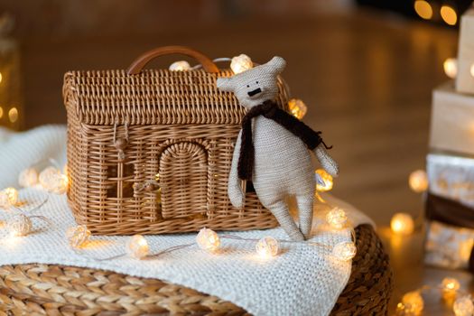 Teddy bear toy on the background of a wicker house made of rattan among Christmas garlands