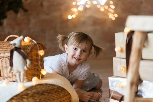 .Cute little girl sitting on the floor among the new year garlands.