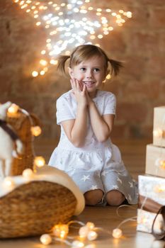 .Adorable little girl sitting on the floor among the new year garlands.