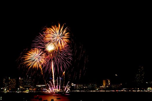 Many flashing fireworks with night cityscape background celebrate New Year.