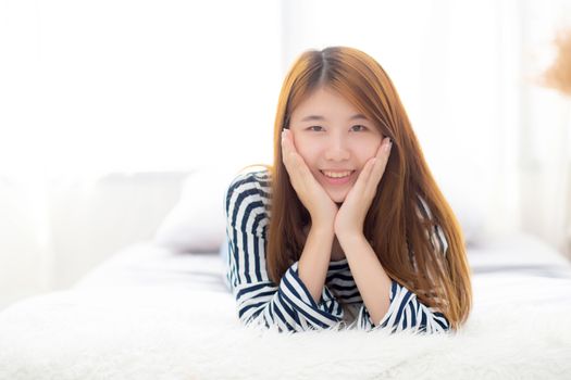 Beautiful portrait young asian woman lying and smile while wake up with sunrise at morning, lifestyle and relax concept.