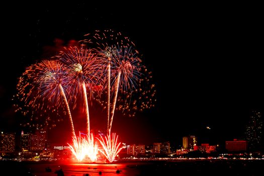 Many flashing fireworks with night cityscape background celebrate New Year.