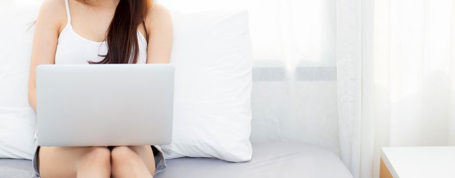 Banner website beautiful young asian woman using laptop for leisure on bedroom, girl working online with notebook freelance, technology and business concept.