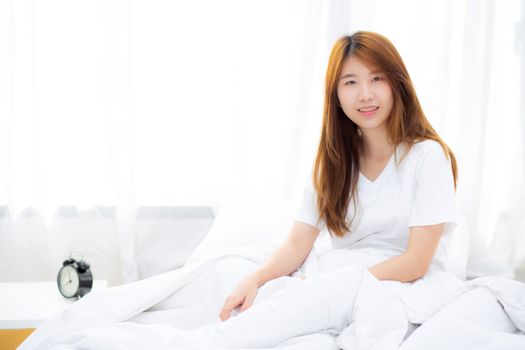 Beautiful portrait young asian woman lying and smile while wake up with sunrise at morning, lifestyle and relax concept.
