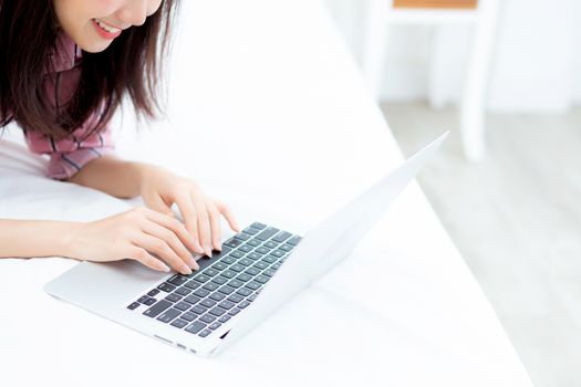 Beautiful asian young woman lying on bed using laptop at bedroom for leisure and relax, freelance with girl working notebook, communication concept.