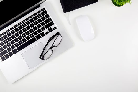 Top view of laptop computer with open display screen monitor, mouse and notepad and glasses isolated on white background, notebook or netbook with keyboard work on desk office, communication technology concept.
