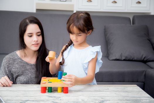 Mother and child play toy together on the living room at home, kid with developing learning for education with activity with family, mom teaching daughter with fun and skill in pastime.