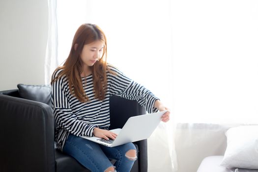 Beautiful of portrait young asian woman using laptop computer  for leisure on chair at living room, girl working online with notebook freelance, communication business concept.