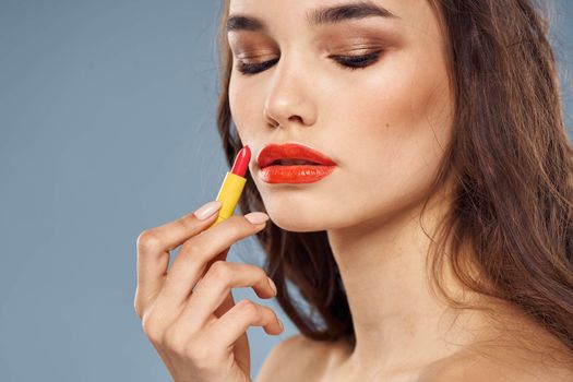 Woman with lipstick on a gray background brunette makeup with eye shadow on the eyelids. High quality photo