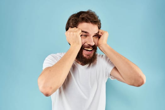 Emotional man with a beard in a white t-shirt blue background fun lifestyle. High quality photo