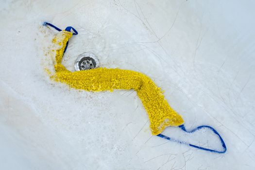 The washcloth lies in the bathtub in foam surrounded by water