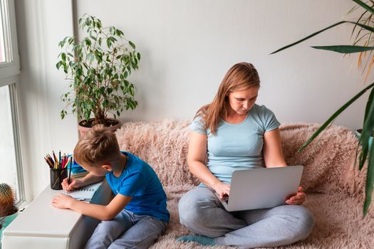 Mother with kid trying to work from home during quarantine. Stay at home, work from home concept during coronavirus pandemic