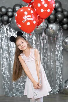 Little girl with red balloons celebrates her birthday.