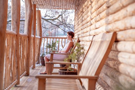 woman relaxes after sauna in a wooden log cabin in winter.