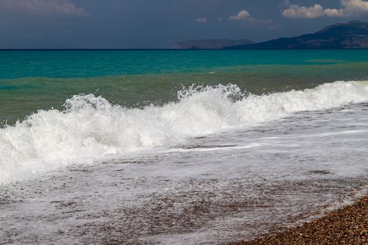 Gravel / pebble beach at the westcoast of Rhodes island near Kattavia with ocean waves and turquoise water