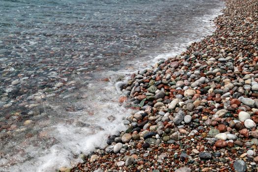 Gravel beach at Kiotari on Rhodes island, Greece with stones in different colours and crystal clear water