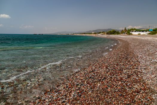 Gravel beach at Kiotari on Rhodes island, Greece with stones in different colours and turquoise clear water