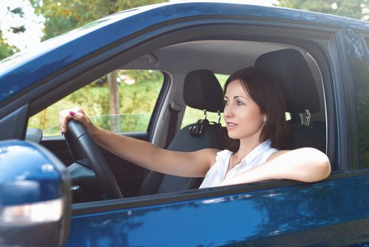 Beautiful adult happy woman driving her car in sunny summer day