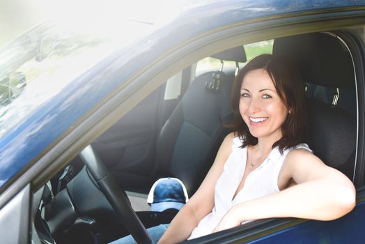 Happy adult woman driving a car and smiling. success happy brunette woman is driving a car. Portrait of happy woman driver.